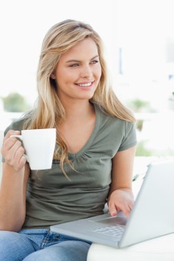 Woman looking slightly to the side, as she holds a cup in her ha clipart