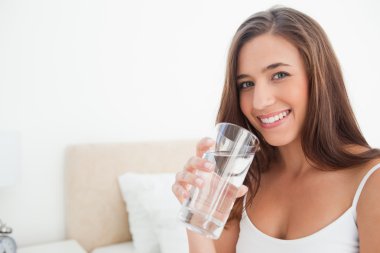 Woman smiling as she holds a glass of water, clipart