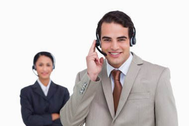 Smiling hotline employee with co-worker behind him clipart