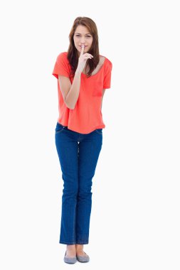 Young woman standing up while showing a quiet gesture clipart