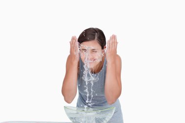 Young woman washing her face with a splash of water clipart
