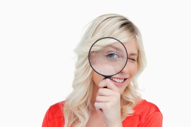 Woman looking through a magnifying glass while blinking an eye clipart