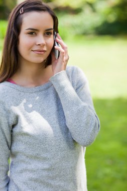 Young serious woman calling with her cellphone while standing in clipart