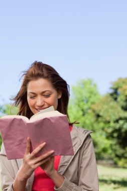 Woman happily reading a book with the wind blowing through her h clipart