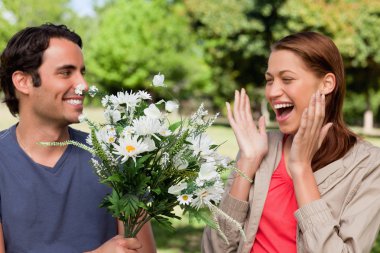 Woman laughing excitedly as she is presented with flowers by her clipart