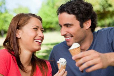 Two friends laughing while holding ice cream clipart