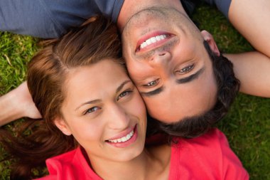Close-up of two friends looking upwards while lying head to shou clipart