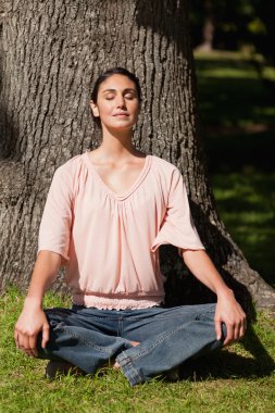 Woman sitting in a yoga pose with her hands placed on her knees clipart