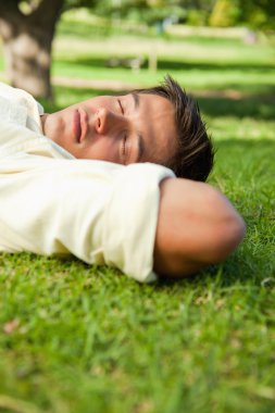 Man lying with his eyes closed and the side of his head resting clipart