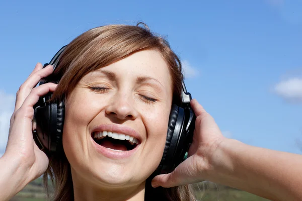 Радостная женщина слушает музыку на открытом воздухе — стоковое фото