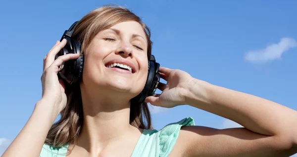 Mulher alegre está ouvindo música ao ar livre — Fotografia de Stock