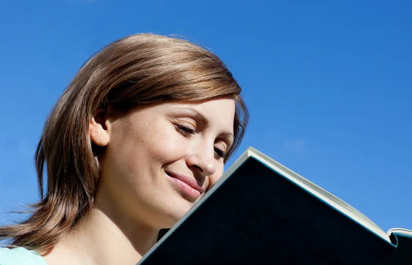 Mulher encantada está lendo um livro ao ar livre — Fotografia de Stock