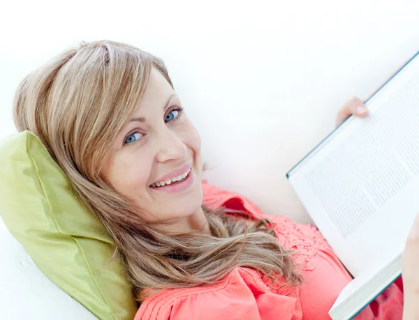 Mujer feliz leyendo un libro acostado en un sofá —  Fotos de Stock