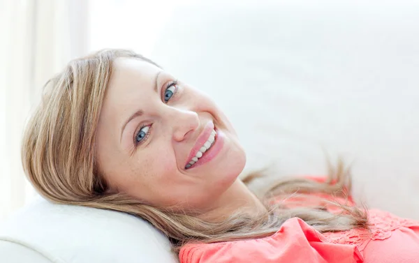 Porträtt av en leende kvinna liggande på en soffa — Stockfoto