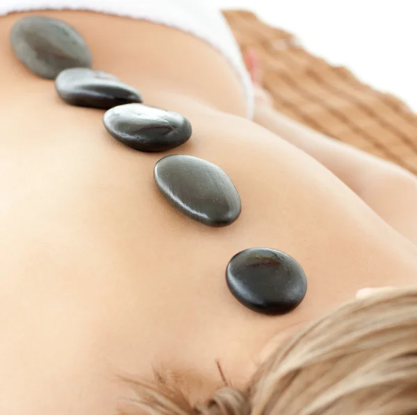 Avslappnad kvinna liggande på en massagebänk med stenar — Stockfoto