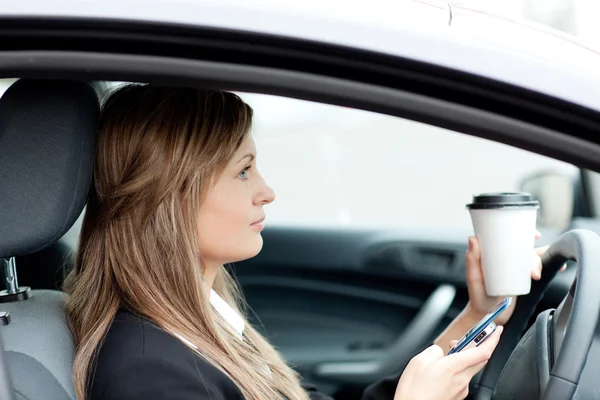 Mujer rubia de negocios enviando un mensaje de texto mientras conduce — Foto de Stock