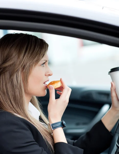Attraktiva affärskvinna äta och hålla en mugg samtidigt — Stockfoto