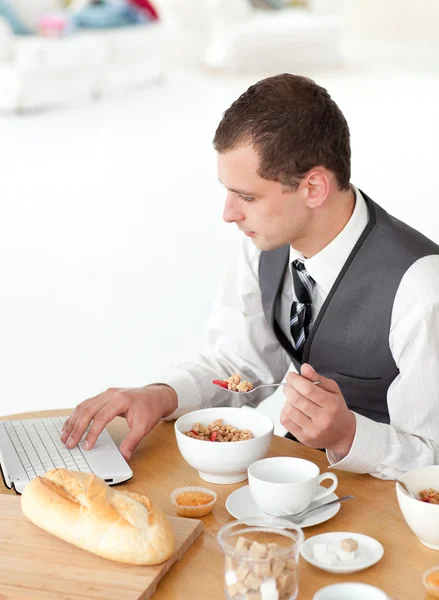 Genç işadamı Kahvaltı yaparken bir dizüstü bilgisayar kullanarak — Stok fotoğraf