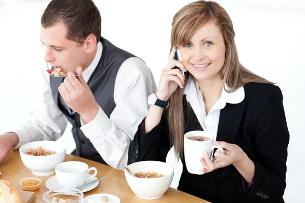 Souriant femme d'affaires parlant au téléphone tout en prenant le petit déjeuner wi — Photo