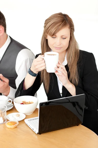 Mujer de negocios seria usando un ordenador portátil mientras desayuna — Foto de Stock