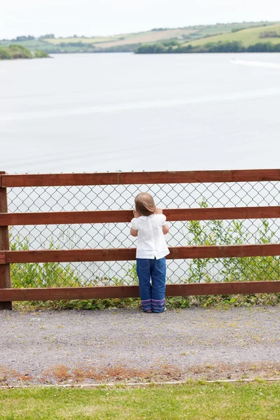 stock image Little child standing in front of a fence