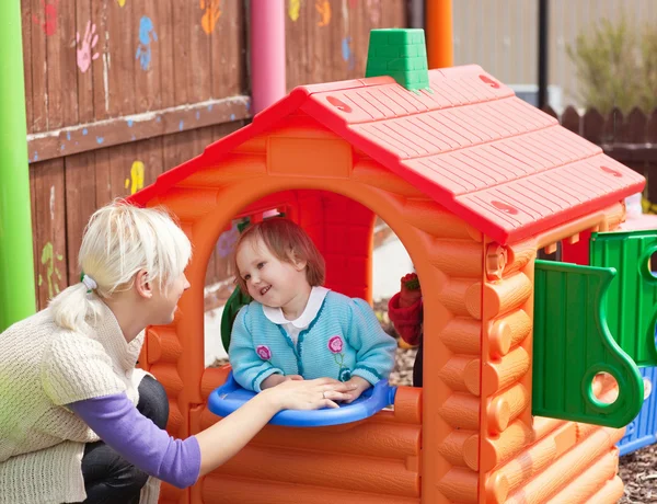 Söt flicka står i ett litet hus på lekplatsen — Stockfoto