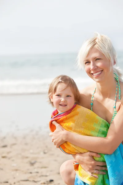 En glad tjej och hennes leende mamma på stranden — Stockfoto