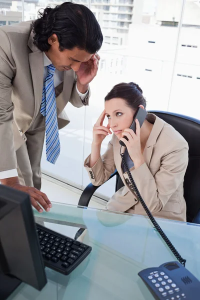 Retrato de una mujer de negocios en el teléfono mientras trabajaba con un empleado —  Fotos de Stock