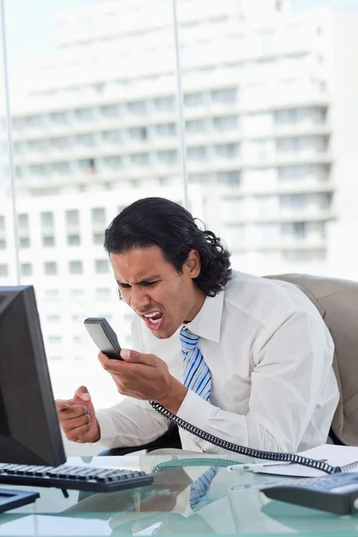 Porträt eines wütenden Geschäftsmannes, der sein Mobiltelefon anbrüllt — Stockfoto