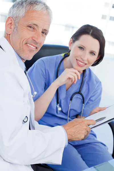 Retrato de uma equipe médica sorrindo procurando um documento — Fotografia de Stock