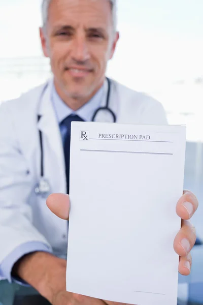 Porträt eines männlichen Arztes, der einen leeren Rezeptbogen zeigt — Stockfoto