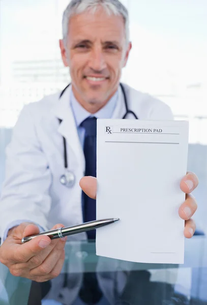Retrato de um médico mostrando uma folha de prescrição em branco — Fotografia de Stock