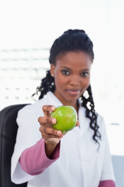 Portrait d'une femme médecin montrant une pomme — Photo