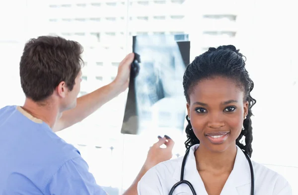 Docteur regardant une radiographie pendant que son collègue pose — Photo