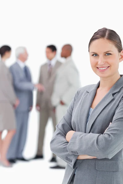 Smiling saleswoman with arms folded and colleagues behind her — Stock Photo, Image