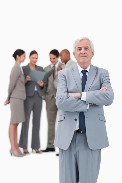 Mature businessman with arms folded and team behind him — Stock Photo, Image
