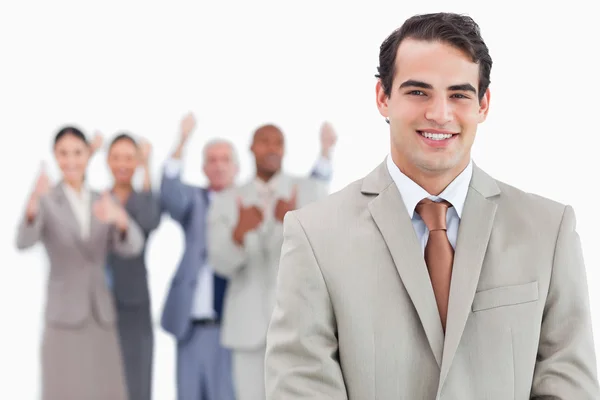 Smiling salesman with cheering team behind him — Stock Photo, Image