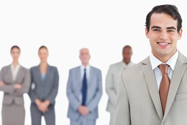 Smiling salesman with colleagues behind him — Stock Photo, Image