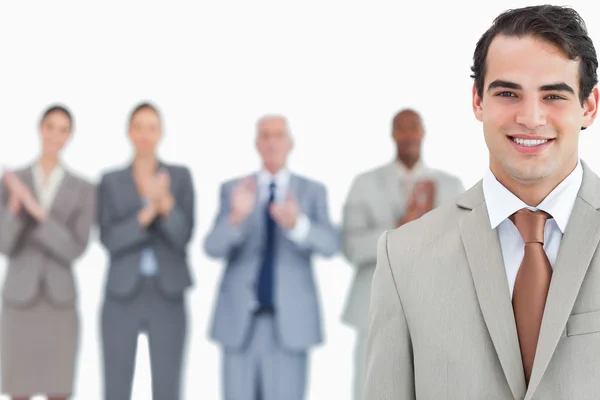 Businessman with applauding colleagues behind him — Stock Photo, Image