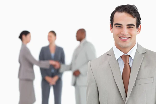 Smiling salesman with businesspeople behind him — Stock Photo, Image