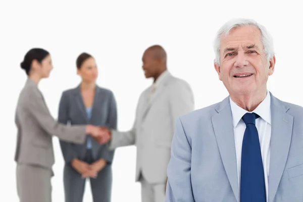 Mature salesman with trading partners behind him — Stock Photo, Image