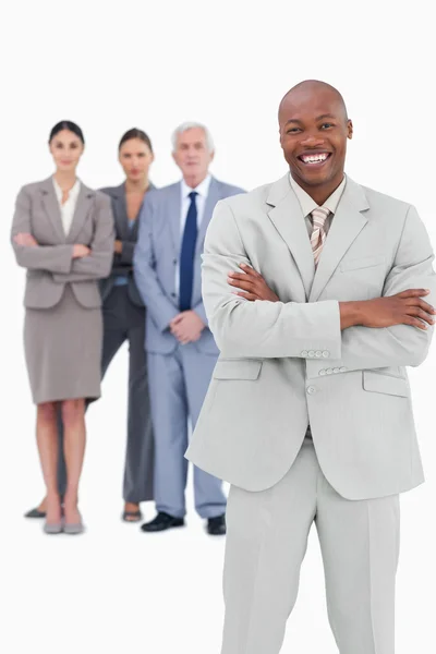 Smiling businessman with arms folded and team behind him — Stock Photo, Image