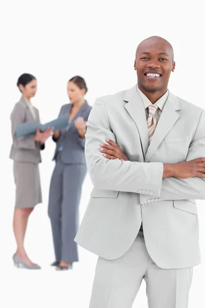 Smiling businessman with arms crossed and colleagues behind him — Stock Photo, Image