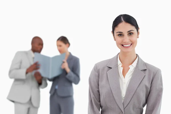 Vendedora sorridente com colegas de trabalho por trás dela — Fotografia de Stock