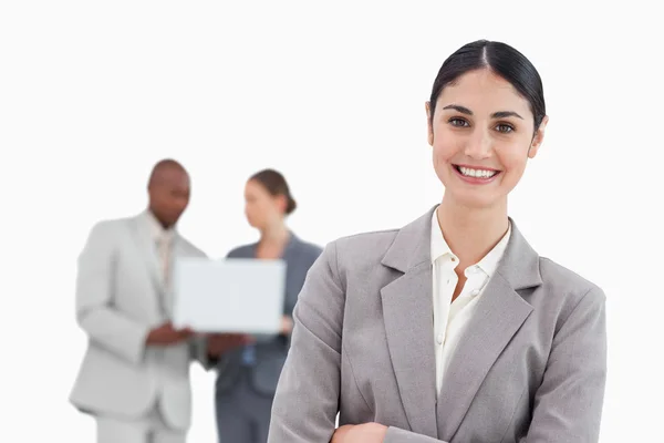 Glimlachende zakenvrouw met collega's achter haar praten — Stockfoto