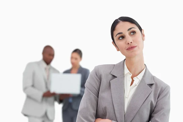 Daydreaming businesswoman with colleagues behind her — Stock Photo, Image