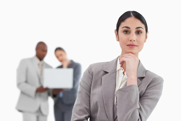 Thinking saleswoman with colleagues behind her — Stock Photo, Image