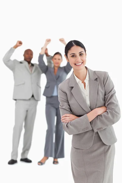 Smiling businesswoman with cheering colleagues behind her — Stock Photo, Image