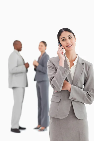 Businesswoman with cellphone and colleagues behind her — Stock Photo, Image