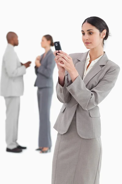Affärskvinna läser textmeddelande med kollegor bakom — Stockfoto